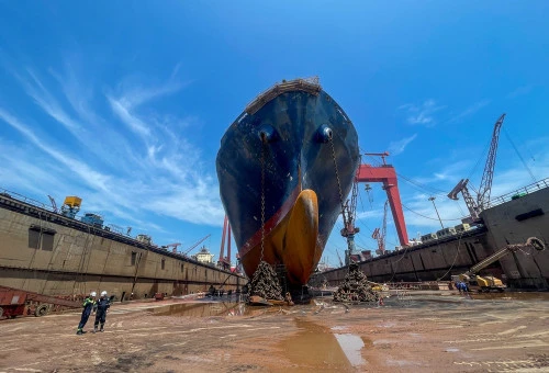 05.08.2024 Qingdao, Chine Vue frontale d'un grande cargo en cale sèche avec des ouvriers, des ancres et des grues visibles dans un chantier naval.