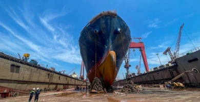 05.08.2024 Qingdao, Chine Vue frontale d'un grande cargo en cale sèche avec des ouvriers, des ancres et des grues visibles dans un chantier naval.